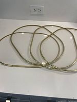 Four vintage oval acrylic placemats stacked, showing gold rims and clear centers.