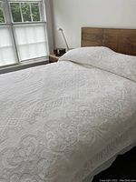 Bedspread spread on queen size bed showing overall pattern and design in natural light near window.