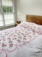 Full view of the bed with the chenille bedspread displayed, showing flower and ribbon pattern and fringed edges.