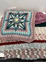 Photo showing folded crochet pillow with starburst pattern and crochet blanket underneath