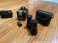 Overall view showing Kodak camera, Leitz binoculars with leather case, and 35mm film spool.