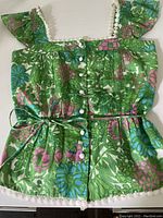 Front view of vintage Milly of New York top featuring colorful floral cotton fabric, button front detail, lace trim, and tie belt.