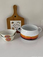 Full view of the lot items including large pot, two small floral bowls, and wooden board with ceramic insert
