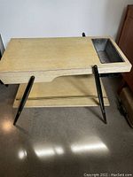 Front view of vintage wooden table showing planter insert and drawer on top, supported by black angled legs.