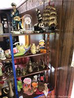 Close-up of sailor figurine beside glass dome clock with floral design and panda bear figurines on brass panda base.