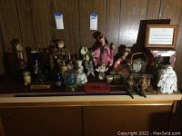 Wide shot of the lot showing various figurines, vases, and framed art on a shelf against a wood paneled wall.