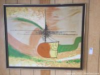 Framed abstract painting with a combination of green, beige, orange colors and black linear details in a dark wood frame hanging on a wood paneled wall.