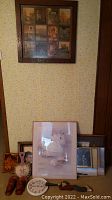 Wall with framed artworks including swan prints, collage, and portraits with Benrus clock on shelf below