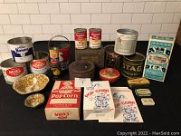 Full assortment of 22 tins and boxes laid out, showing variety in brands and types including honey, peanut butter, popcorn, soup, tea and tobacco.