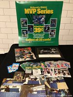 Full view of collectibles laid out on table under McDonald's Donruss MVP Series promotional sign, showing cards, magazine, autographed card, and photos.