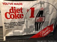 Front view of large Diet Coke poster with red and black text, bottle image and Toronto reference.