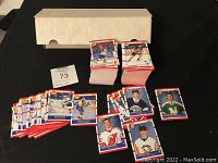 Photo showing multiple stacks of hockey cards laid out next to a box, displaying several individual cards face up against a black background.