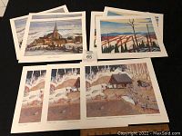 Nine prints laid out showing landscape scenes including snowy rural cabins and rolling hills.