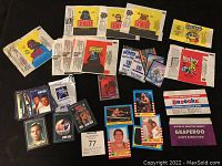 Photo of assorted vintage collector cards and candy wrappers spread out on black background.