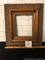 Full front view of the antique wooden picture frame showing carved outer border and decorative metal inner trim.