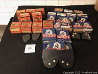 Photo of boxes of Safeheel rubber heels stacked on the left side and Biltrite rubber heels boxes stacked on the right side with pairs of black rubber heels laid out in front.