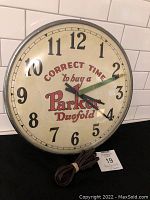 Front view of full clock face showing “Correct time to buy a Parker Duofold” text and pen-shaped second hand