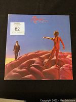 Front cover of the RUSH Hemispheres album with surreal artwork, showing a naked man on a brain and a suited man with a cane against a blue sky.