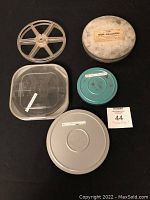 Top-down view of three metal film cans with two film reels showing their size and condition including a labeled "Non-Halation" can.