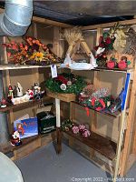 Wide view of shelves displaying various Christmas decorations including wreaths, pinecones, figurines, and nativity scene.