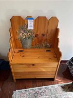 Front view of the oak bench showing floral painting on the backrest and seat lid closed.