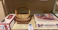 View of the three small wicker baskets, box of Solo plastic forks, and part of the pallet showing the serving set box.