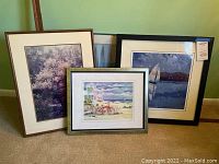 Four matted and framed art prints leaning on a wall, showing variety of styles and sizes.