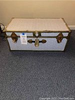 Closed front view of white camp trunk showing brass-colored locks, latches and trim.