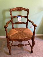 Front view of wood armchair showing rush seating and overall design.