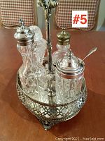 Antique Sheffield plate cruet stand with four cut glass containers viewed from side showing ornate pierced floral design and four feet.