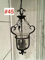 Front view of the black metal light fixture showing intricate curved arms and clear glass shade.