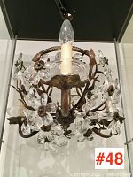 Frontal view of chandelier showing metal floral frame with clear crystal flower clusters and single faux candle bulb sleeve.