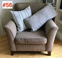 Front view of corduroy upholstered armchair with two throw pillows placed on the seat. Chair is brown corduroy with ribbed texture, includes one striped pillow and one solid light pillow.