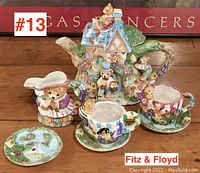 Full view of Fitz & Floyd collectible tea set pieces on wooden surface showing multiple ceramic items with animal-themed designs.