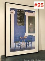 Full view of the framed poster showing the blue wall with window, menu board, two blue chairs and small table with drinks.