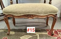 Front view showing curved apron with central floral carving and upholstered seat