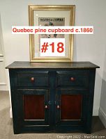 Front view of Quebec pine cupboard showing two drawers over two doors, painted dark blue with red panels and round wooden knobs.