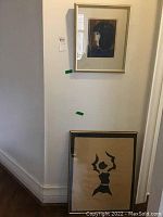 Two framed artworks leaning against wall
