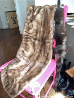 Light brown mink fur stole draped over a pink chair with darker shaded portions and a shiny texture visible.