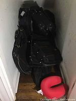 General overview showing stacked black luggage pieces with handles and wheels and red travel neck pillow at floor.