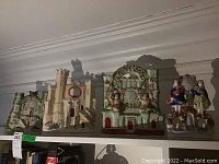 Four porcelain decorative pieces on a high shelf showing details and overall set