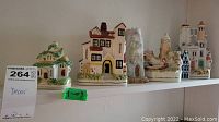 Five porcelain house figurines arranged on a shelf, showing variety in size and design