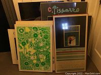 Seven posters leaning against wall and TV stand