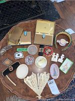 Top view of all lot items on a wooden table including brass cases, trinket dishes, fan, figurines, clock, and headband.