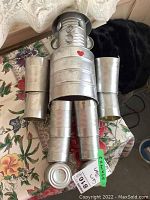 Front view of tin can man with arms spread, showing the heart detail and button eyes.