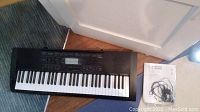 Casio CTK-3000 keyboard on the floor next to the instruction manual and headphones.