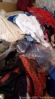 Pile of assorted women's clothing items in various colors and fabrics seen in a heap on furniture.