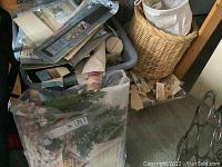 View of assorted crafting supplies in bins and basket, including papers and materials scattered