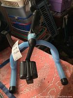 Front view of lightweight cycle exerciser showing blue frame and black pedals with straps.