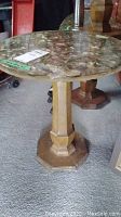 Side angled photo showing round shell inlay top and wooden octagonal pedestal base of the end table.